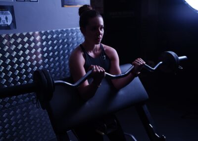 Focused woman weightlifting with barbell in a Paris gym, highlighting strength and determination.