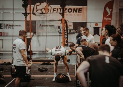 Group of athletes engaging in a competitive CrossFit workout at a gym with emphasis on strength and teamwork.