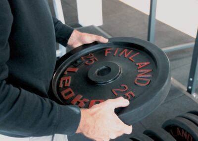 Close-up of a person holding a 25 kg weight plate in a gym.