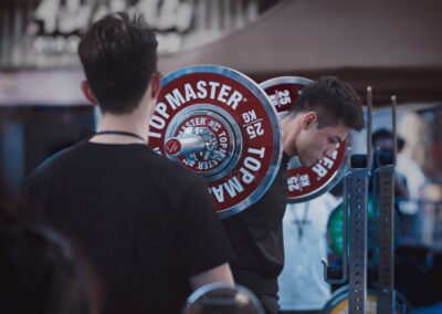 Man lifting weights at an outdoor competition, showcasing strength and focus.