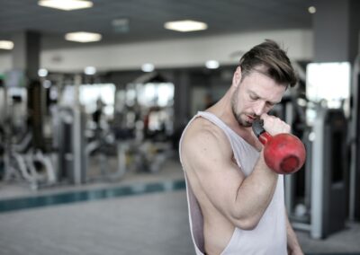 An athletic man working out with a kettlebell in a gym setting, emphasizing strength training.