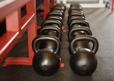 Black kettlebells lined up in a gym, ready for fitness training.
