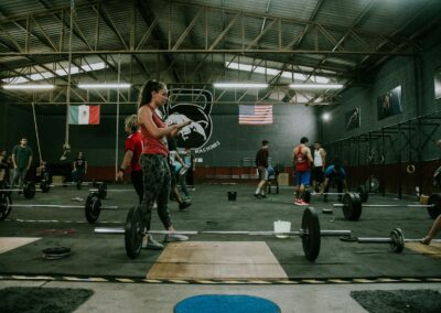 Group of adults practicing CrossFit with weights in an industrial-style gym.